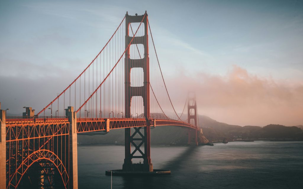 Golden Gate Bridge shrouded in fog during sunset, San Francisco.