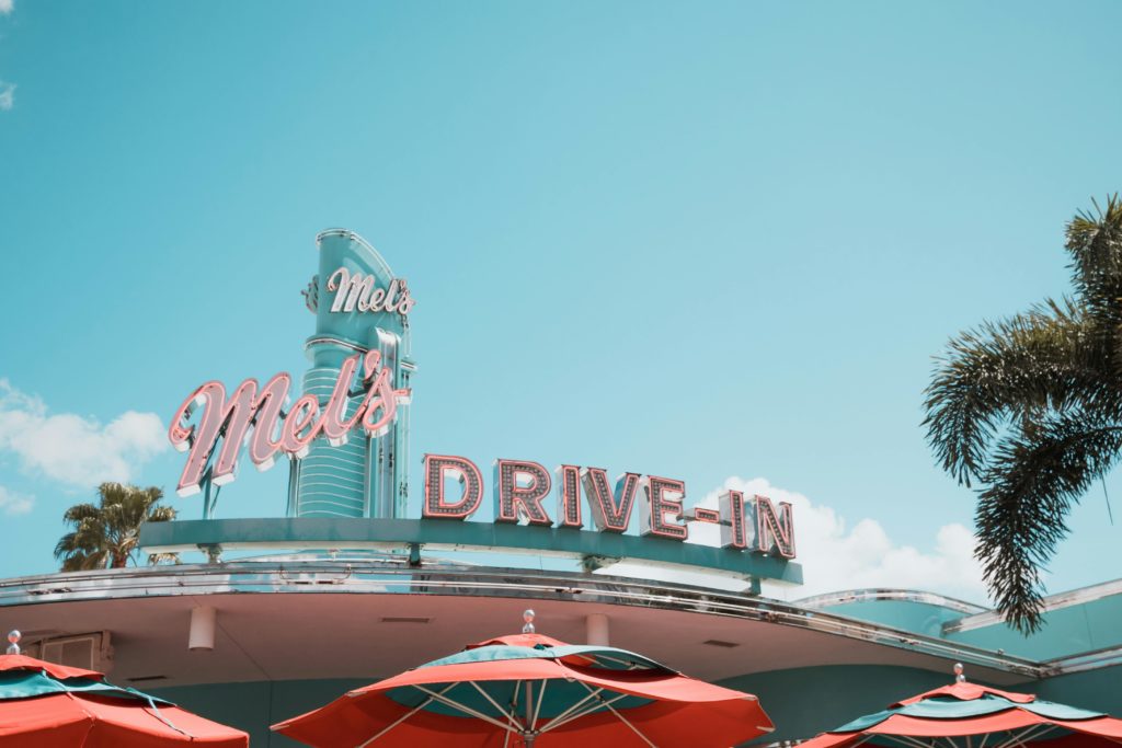A vintage drive-in diner featuring classic neon signage and vibrant red umbrellas.