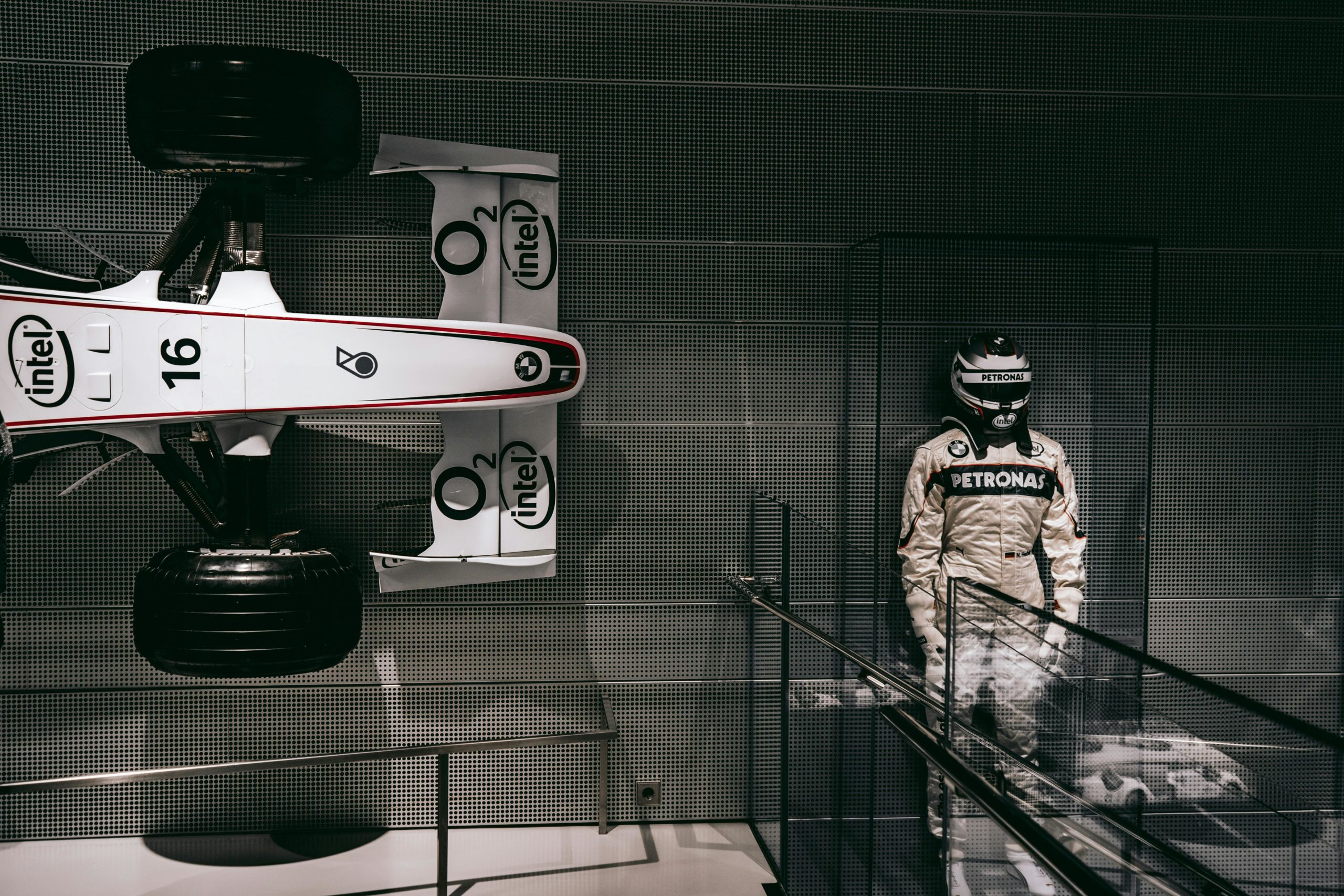 Showcasing a race car and driver suit in a sleek Munich exhibit.