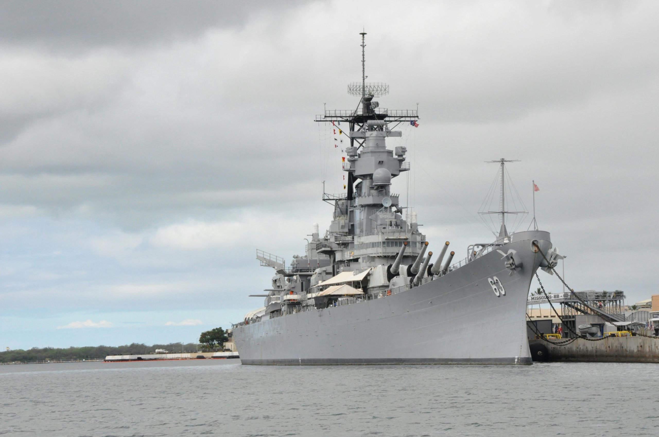 USS Missouri battleship moored at Pearl Harbor in Hawaii under a cloudy sky.