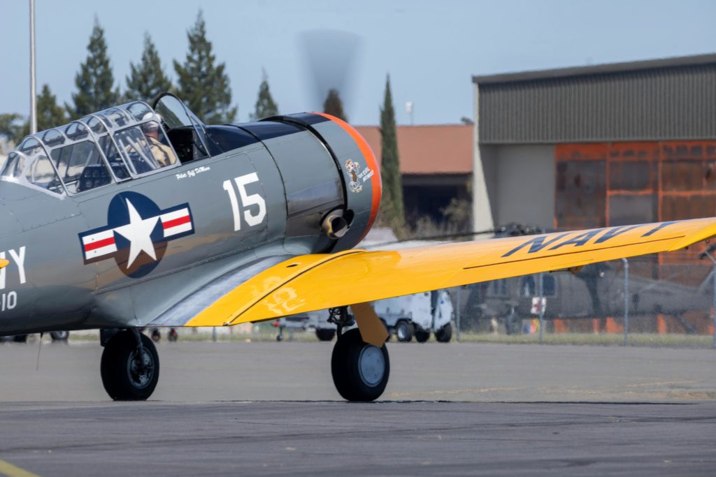 Close-up of a vintage navy aircraft taxiing on the runway, highlighting its classic design.